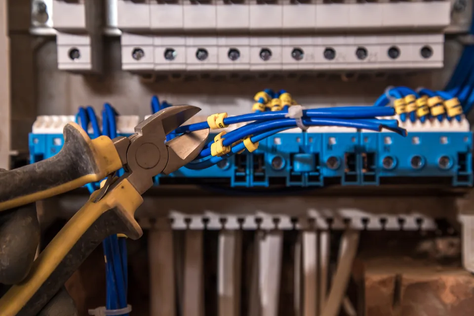 Close-up of electrical panel wiring, circuit breakers and insulated pliers